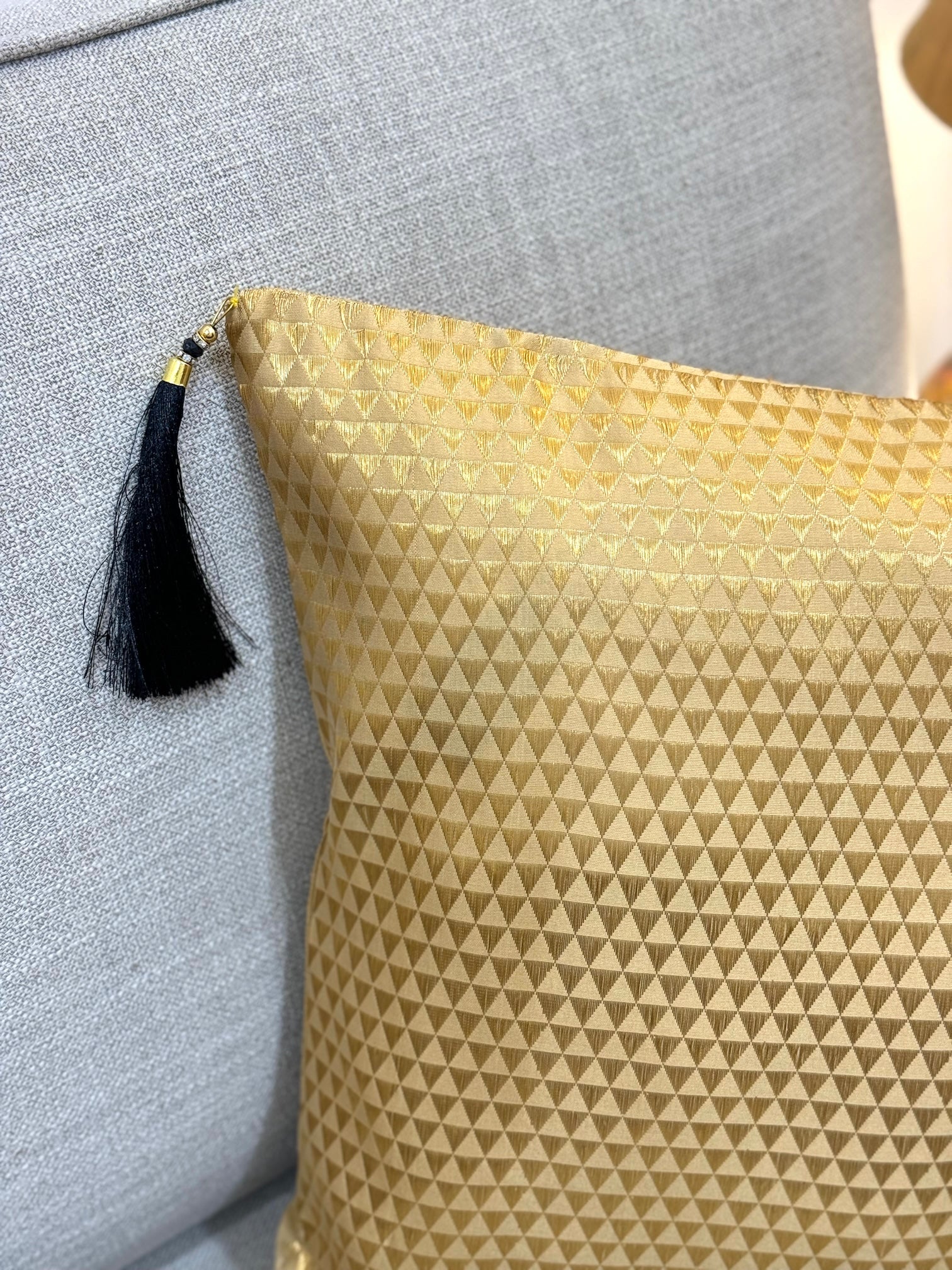 golden brocade cushion cover with black rtassels
