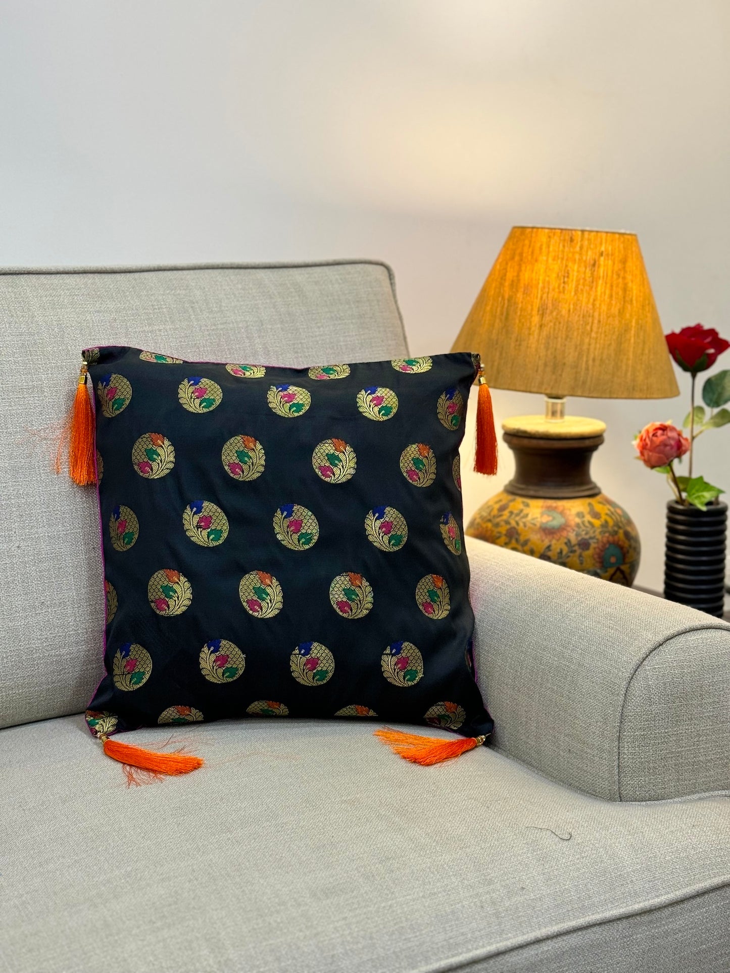 black and gold brocade cushion cover with orange tassels
