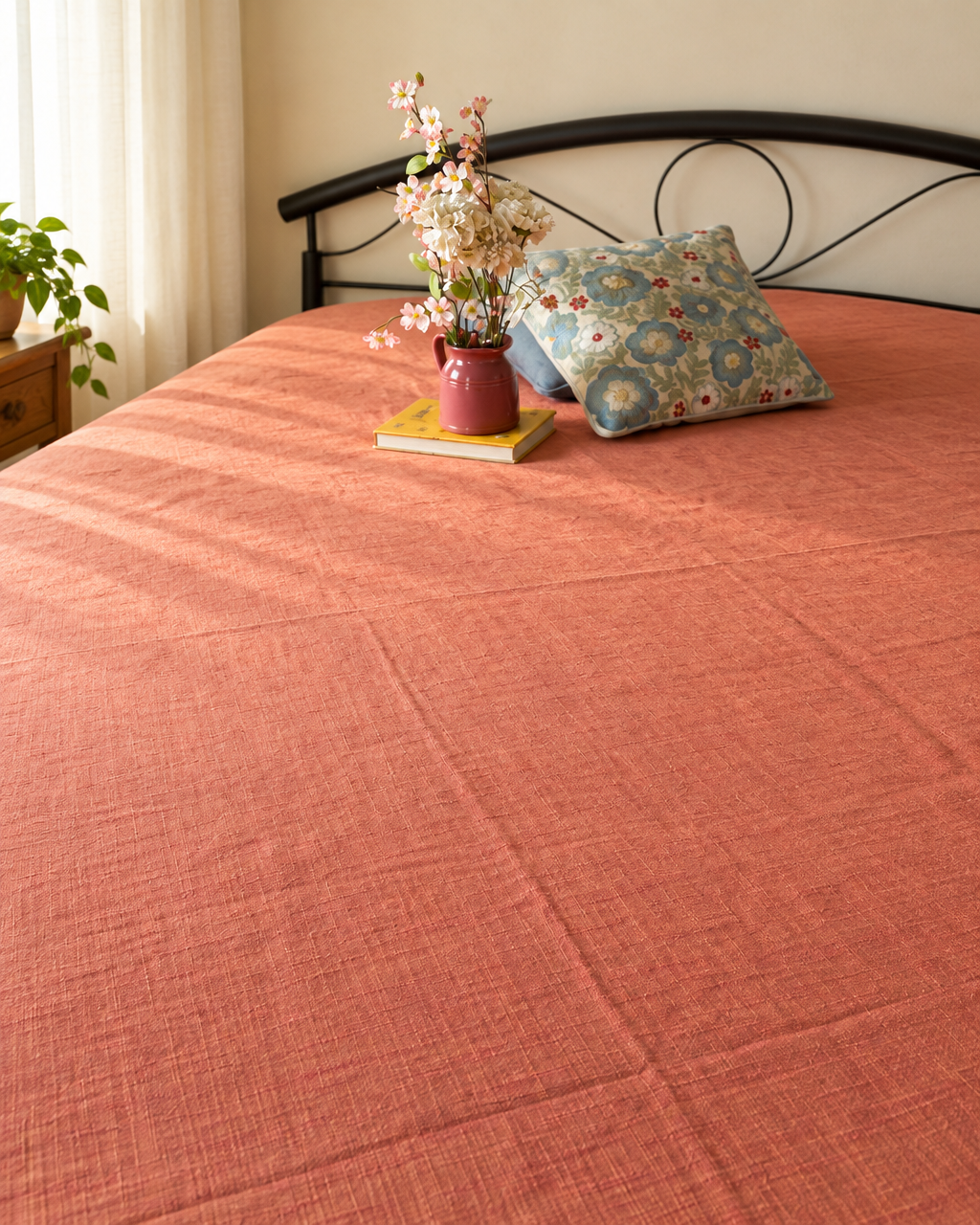 rust handloom bedcover with cushion and flowers flatlay